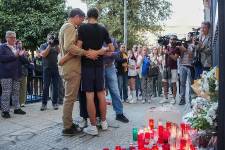 Familia de Sandra se abraza frente a un memorial conmemorativo.