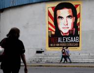 AME337. CARACAS (VENEZUELA), 17/10/2021.- Personas pasan frente a un cartel de apoyo al empresario colombo-venezolano Alex Saab hoy, en Caracas (Venezuela).