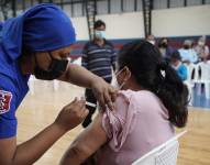 Quito.- Un trabajador de la salud aplica una vacuna contra el COVID-19 a una ciudadana en el Coliseo de Calderón, al norte de la capital.