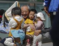 Imagen de mayo de 2021.- Un adulto mayor juega con niños cerca de un edificio de oficinas en Beijing.