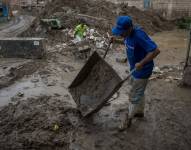 Foto del pasado 18 de octubre en la que se registró a dos hombres al limpiar una calle afectada.