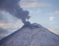 Fotografía del volcán Cotopaxi, con una fumarola de gas y ceniza, visto desde la ciudad de Quito.