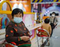 Una mujer protegida con una mascarilla utiliza su móvil en un centro comercial de Pekín. EFE/EPA/WU HAO