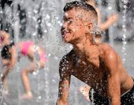 Un niño se refresca en una fuente del centro de Duisburg (Alemania) por las altas temperaturas.