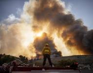 Fotografía de archivo de un bombero observa el humo que se eleva al sur de Los Ángeles, California.