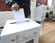 Una persona depositando su voto en una urna.
