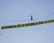 Una activista de Greenpeace recorre una cinta suspendida a 30 metros de altura en pleno centro de Madrid, junto con una pancarta con la inscripción El planeta, en la cuerda floja