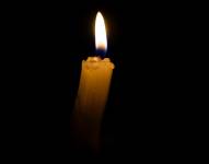 Imagen de una vela encendida en medio de la oscuridad.