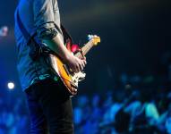 Imagen de un hombre tocando una guitarra en un concierto.