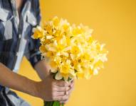 Persona entregando un ramo de flores amarillas.