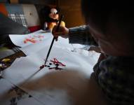 Esta foto tomada el 8 de abril de 2025 muestra a la artista de 21 meses Pulgarcita (derecha) usando un pincel para pintar en la casa de su familia en Tokio.