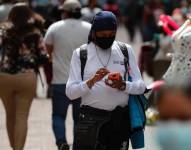 Persona revisa su celular en las calles de Quito.
