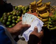 Fotografía de archivo fechada el 23 de septiembre de 2022 que muestra a un vendedor informal que cuenta billetes de bolívar en el mercado de Quinta Crespo, en Caracas (Venezuela).