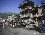Bomberos están parados junto a los restos de un camión que trasportaba gasolina después que volcó y estalló en Cabo Haitiano, Haití, martes 14 de diciembre de 2021.