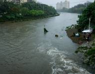 Hombres pescan a lo largo de un río crecido en Beijing, China, 31 de julio de 2023.