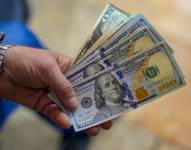 Un cajero muestra billetes de dólares estadounidenses en una casa de cambio.