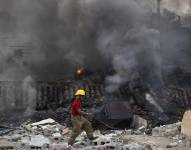 Un integrante de los bomberos pasa frente a locales afectados por una explosión en San Cristóbal, República Dominicana.