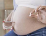 Mujer embarazada con una pastilla.