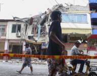 Personas pasan frente a una edificación afectada por un terremoto de magnitud 6,5 en Pasaje.