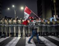 Una persona sostiene una bandera de Perú frente a integrantes de la Policía de Perú durante una manifestación este miércoles, en Lima (Perú).