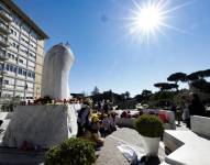 Niños de una escuela primaria en Rivoli, cerca de Turín, rezan frente a la estatua de Juan Pablo II en la entrada del Hospital Gemelli, donde está hospitalizado el Papa Francisco, en Roma, Italia, 18 de marzo de 2025.