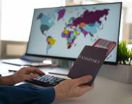 Imagen referencial de hombre con pasaportes observando un mapa en su laptop.