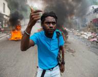 Un hombre hace un gesto cerca de neumáticos en llamas durante una protesta contra la inseguridad en Puerto Príncipe el 16 de abril de 2025.