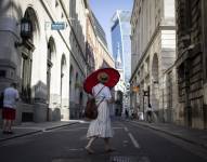 Una mujer en Reino Unido se protege del calor con una sombrilla.
