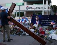 Un hombre carga una gran cruz cerca de un monumento improvisado en honor a Charlie Kirk, fundador de Turning Point USA, frente a la sede de Turning Point USA en Phoenix, Arizona, el 12 de septiembre de 2025.