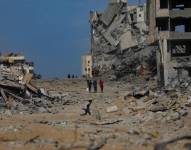 Palestinos caminan por una calle destruída por los bombardeos israelíes en Gaza.