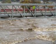 Personas cruzan un puente sobre un crecido río Los Ángeles, el 14 de enero de 2023, en Los Ángeles. (AP Foto/Damian Dovarganes)