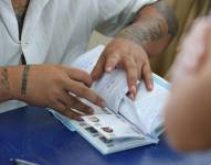 Imagen del secretario de una junta receptora de votos revisando los certificados de votación para entregar a un ciudadano que acaba de ejercer su derecho al sufragio, este domingo 9 de febrero.