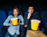 Cinema day, young couple with popcorn looking horror movie in cinema at their date.
