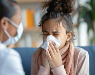 Niño enfermo soplando su moco en un pañuelo.