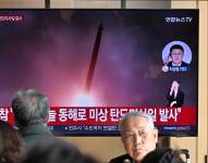 La gente al rededor de un televisor mirando las noticias con un video de una prueba de misiles de Corea del Norte.