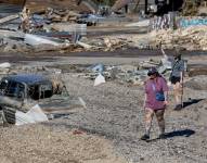 Personas caminando junto a un vehículo afectado luego de las inundaciones provocadas por la tormenta tropical Helene en Ashevill.
