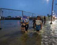 Un grupo de personas fue registrado este martes, 20 de febrero, al caminar por una vía inundada, debido a las fuertes lluvias, en Guayaquil.