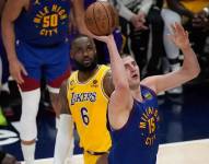 Nikola Jokic lanzando sobre la mirada pasiva de Lebron James.