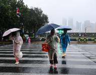 La gente se protege con una funda desechable para la lluvia durante el paso del tifón Co-May en Shanghái el 30 de julio de 2025. Shanghái ha evacuado a casi 283 000 personas de zonas costeras y bajas vulnerables ante la proximidad del tifón Co-May, que trae lluvias torrenciales y fuertes vientos, según informaron los medios estatales el 30 de julio.