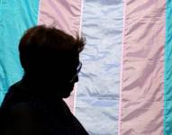 Una persona detrás de una bandera que promueve el orgullo trans.