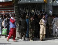 Afganos hacen largas filas el domingo 15 de agosto de 2021 para retirar dinero de un banco, en Kabul, Afganistán.