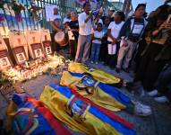 Familiares de los cuatro menores del caso Las Malvinas, quienes fueron encontrados muertos cerca de una base militar, yacen en el suelo cubiertos con banderas ecuatorianas durante una manifestación para exigir justicia, el 8 de diciembre de 2025.
