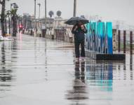 Una persona camina bajo la lluvia en el puerto de Ensenada en Baja California