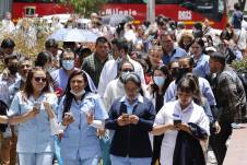Personas usan sus teléfonos afuera de un edificio luego de ser evacuadas debido a un sismo de 6.1 grados.