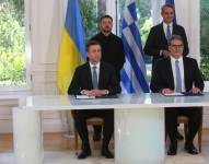 El CEO de DEPA, Konstantinos Xifaras (dcha), y el CEO Naftogaz, Sergeii Koretskyi (izda), firman el acuerdo de energía con la presencia del primer ministro griego Kyriakos Mitsotakis (detrás a la dcha) y el presidente ucraniano Volodímir Zelenski .