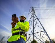 Fotografía sin fecha específica de toma cedida por T-Mobile que muestra a una persona observando su teléfono frente a una torre eléctrica en Estados Unidos.
