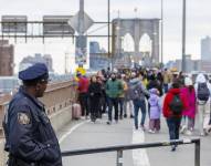Un oficial de policía observa personas caminando por el puente de Brooklyn sin vendedores a la vista en Nueva York.
