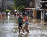 Habitantes transitan por una calle inundada tras las lluvias en el área metropolitana de Río de Janeiro.