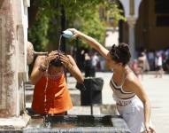 Dos mujeres se refrescan en una fuente del Patio de los Naranjos de la Mezquita Catedral de Córdoba.