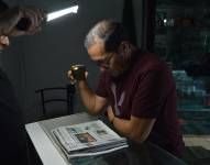 Imagen referencial de una persona alumbrando un periódico con la luz de su celular.